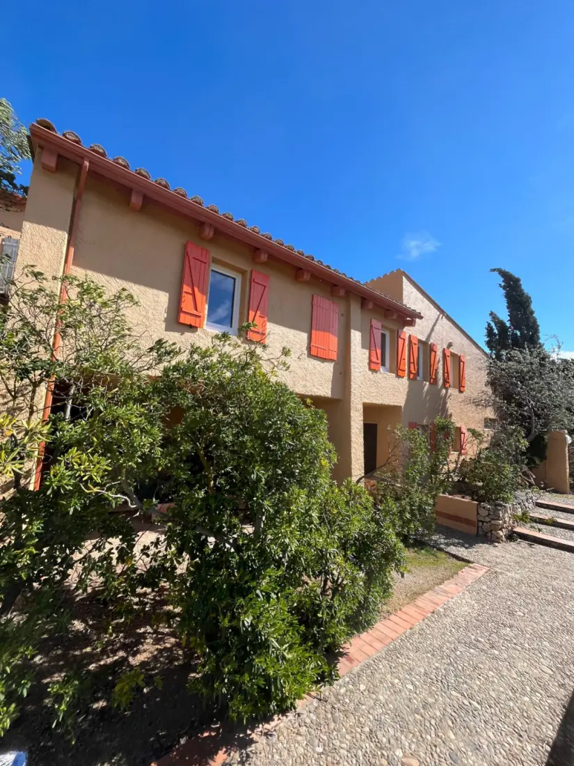 Façade rénovée d'un bâtiment de deux niveaux avec volets bois repeints en orange